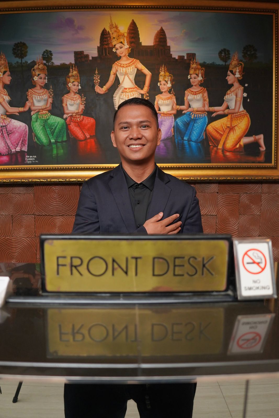 Staf front desk menyambut tamu di depan lukisan penari